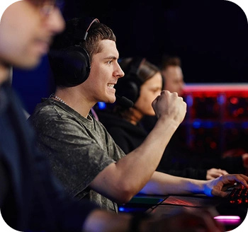 Een e-sportteam speelt wedstrijden op gamecomputers, waarbij een van de spelers een belangrijk moment viert door tijdens een intense online wedstrijd een headset op te zetten.