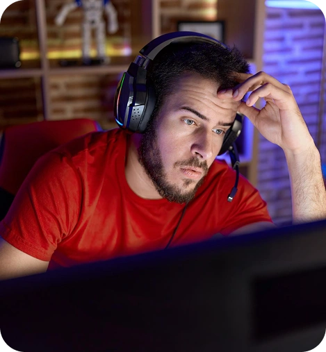 Een geconcentreerde gamer in een rood shirt met een headset op zijn hoofd, terwijl hij zich concentreert op een computerscherm tijdens een intense online wedstrijd.