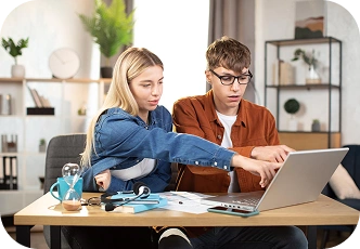 Twee studenten werken thuis samen via een laptop, bespreken hun huiswerk en werken gezamenlijk aan een studentenproject.